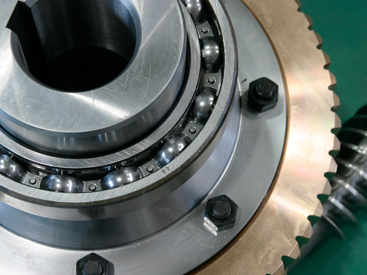 Die speziellen Einzelteile eines Industriegetriebes liegen auf einem tannengrünen Untergrund. KACHELMANN GETRIEBE GmbH